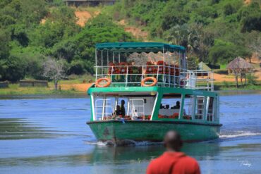 A group of tourists enjoying a safari in Uganda with Cymo African Safaris, spotting wildlife in a lush, green landscape.